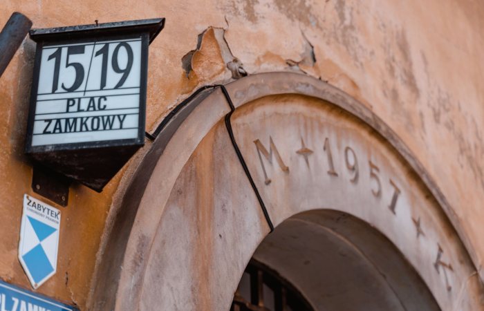 Close-up of a historic archway at Plac Zamkowy, displaying architectural details and signage.